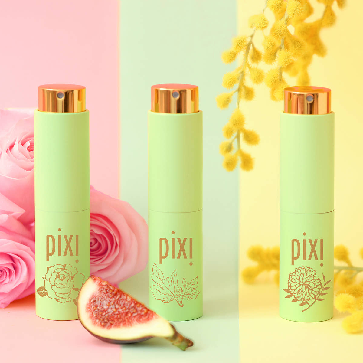 Three Pixi Perfumes in a light mint green color with metallic rose gold caps, arranged on a pastel pink, mint green, and pale yellow background with decorative flowers and a fig slice.