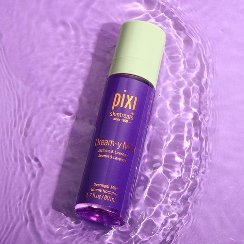 A bottle of PIXI Dream-y Mist sleep spray on a purple background with water ripples around it, indicating movement and freshness.